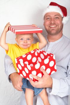 Baby boy with his father for Christmas holding a large gift box