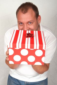 Handsome adult Caucasian man holding a large Christmas gift box with bow