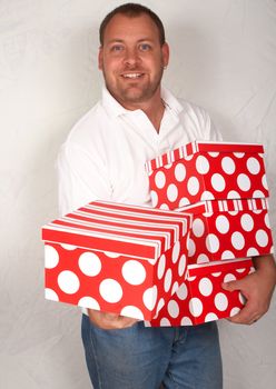 Handsome adult Caucasian man holding large Christmas gift boxes 