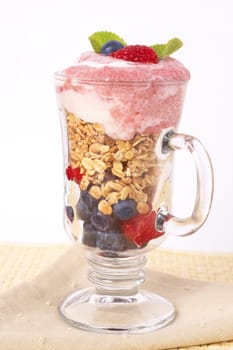 Healthy breakfast with muesli, raspberries, blueberries and yoghurt, decorated with mint leaves in a glass