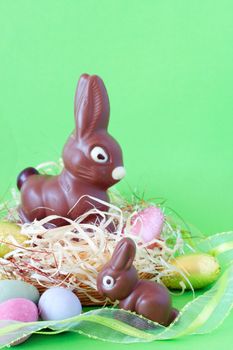 Assortment of chocolate Easter eggs and bunnies in straw on colorful paper