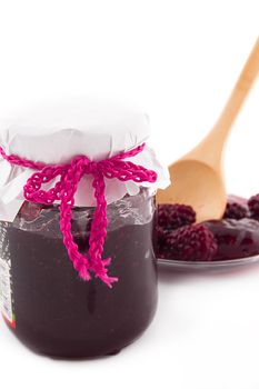 Blackberry jam in bowl and berries on plate and spoon