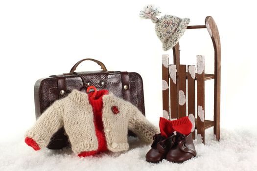 Sled, winter clothes and suitcases in front of white background