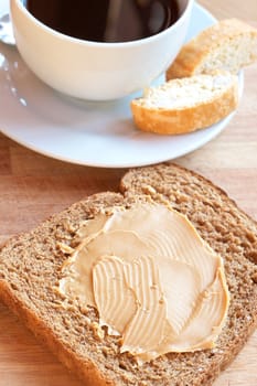 Two slices of Tasty healthy wholewheat bread with peanut butter spread and cup of black coffee on the table