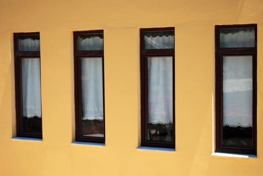 Four Brown Closed Windows on the Yellow Wall