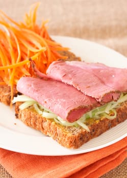 Tasty open sandwich with cucumber relish, smoked beef pastrami and sliced carrots on wholewheat bread 