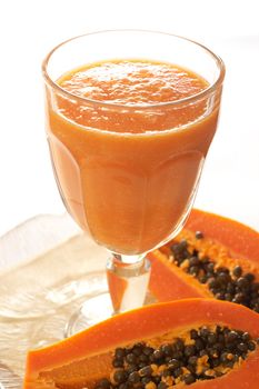 Glass of fresh papaya smoothie with sliced papaya
