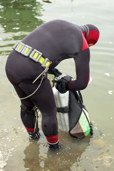 scuba diver in wet suit preparing to enter the cold water