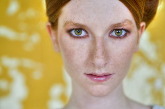 Portrait of a natural redhead in front of a yellow wall