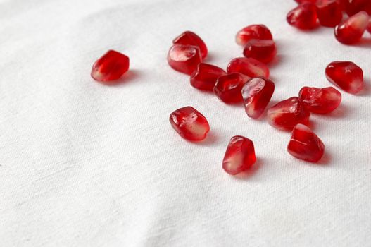 red ripe pomegranate seeds spreaded over white tablecloth