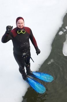 diver in wetsuit standing on river ice