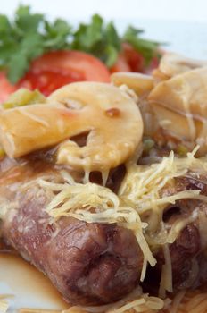 grilled meat rolls with mushrooms, melted cheese and vegetable garnish