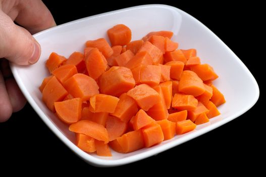 diced carrot on the plate, isolated on black