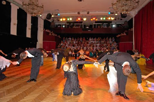 Dancing pairs bow on a background of auditorium                             