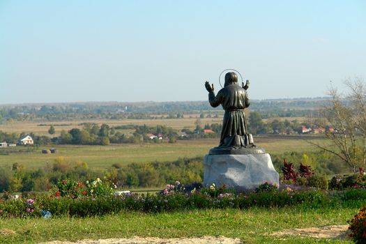 Statue of the eremite which prays on a hum noise of the blue sky                               