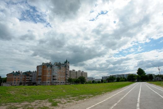 Road and the multi-storey house on a background of the cloudy sky                               