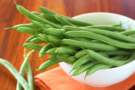 Green beans in a white bowl on orange napkin