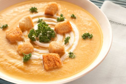 Bowl of fresh hot butternut soup with cream, parsley and croutons