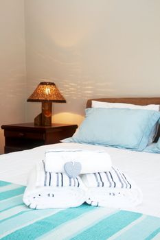 Beautiful bedroom interior with white sheets and striped towels 