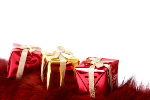 Row of small colorful gift boxes on red fur isolated on white background with copy space