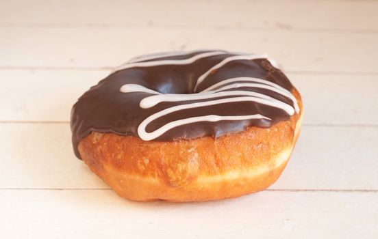 Donut covered in chocolate icing on grunge wooden background