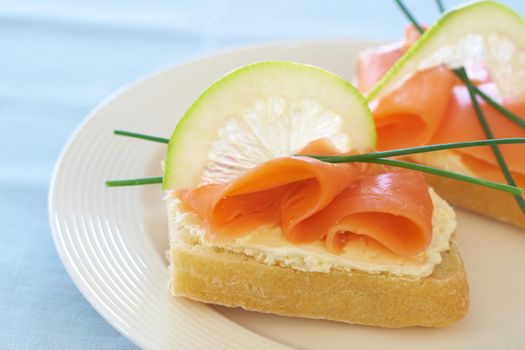 Smoked salmon and cream cheese on white bread with slice of lemon and chives