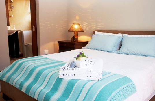 Beautiful bedroom interior with white sheets and striped towels 