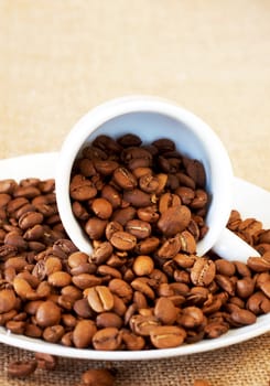 Small espresso cup filled with roasted coffee beans