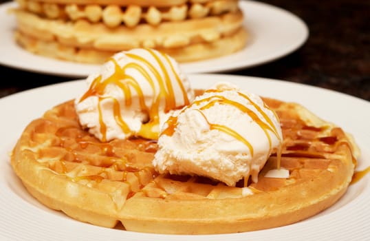 Belgian waffles with ice-cream and syrup on white plate