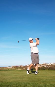 Young male golfer playing off the tee box on a summer day