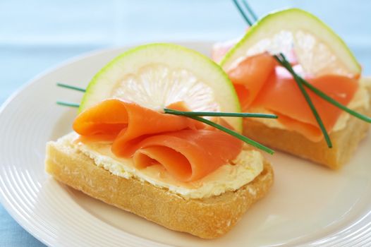 Smoked salmon and cream cheese on white bread with slice of lemon and chives