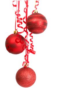 Three red Christmas baubles hanging on a ribbon isolated on white background with copy space. 