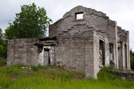 The walls of an abandoned house on a background of green grass.