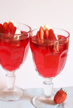 Strawberry jelly with fresh strawberry and cream in tall glasses on white background