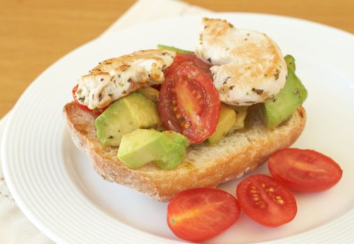 Tasty avocado, baby tomato and grilled chicken bruschetta on ciabatta 