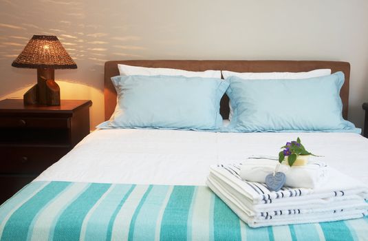 Beautiful bedroom interior with white sheets and striped towels 