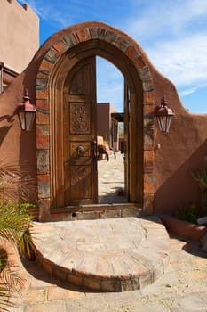 Large, arched, ornate, double door, with brick patio leading to an inner coutyard with seating