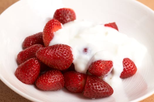 Sliced fresh strawberries with cream in a white plate