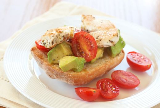 Tasty avocado, baby tomato and grilled chicken bruschetta on ciabatta 