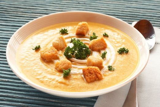 Bowl of fresh hot butternut soup with cream, parsley and croutons