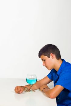 A teenager handcuffed to a cocktail glass, an alcoholism concept