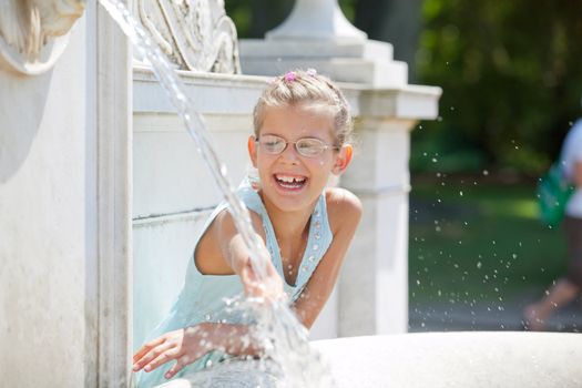 Beautiful girl playing with water in fountain