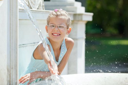 Beautiful girl playing with water in fountain