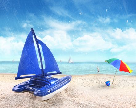 Toy sailboat in sand with beach scene in background
