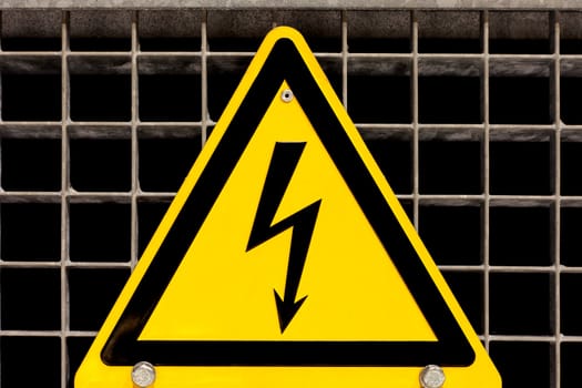 Metal high voltage danger sign bolted to steel grid