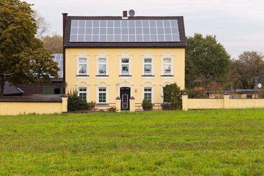 Historic house built 1900 has roof covered with modern solar panels for generating green power.