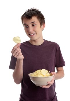 A boy holding  a bowl of potato crisps a single  potato crisp in his hand.  He is looking at it and smiling