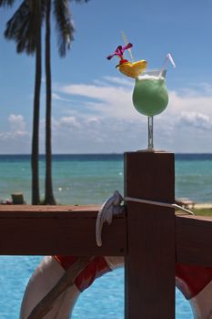 Colorful cocktail with a swimming pool in the background.