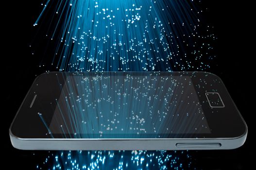 Many illuminated blue fiber optic light strands cascading down against a black background and reflecting on the screen of a smart phone in the foreground