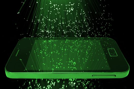 Many illuminated green fiber optic light strands cascading down against a black background and reflecting on the screen of a smart phone in the foreground